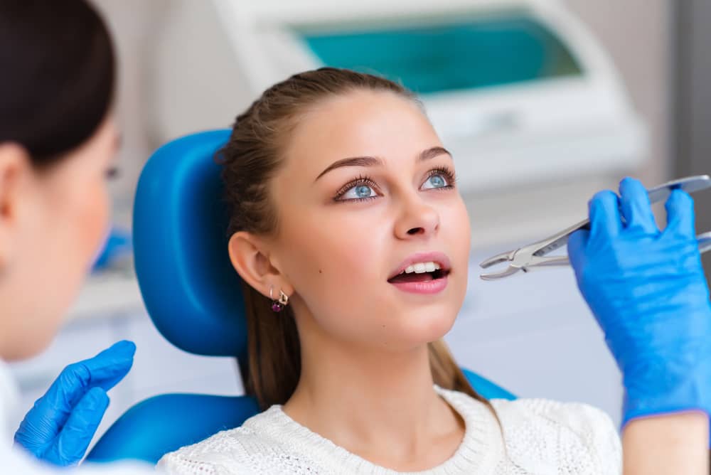 dentist performing extracting tooth using a plier